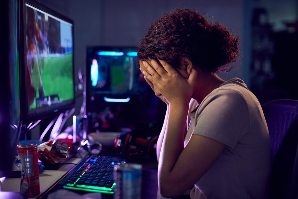 Stressed Teenage Girl Being Bullied Online Whilst Gaming At Home